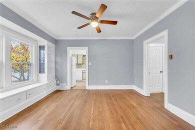 Spare room with ceiling fan, light wood-type flooring, and ornamental molding
