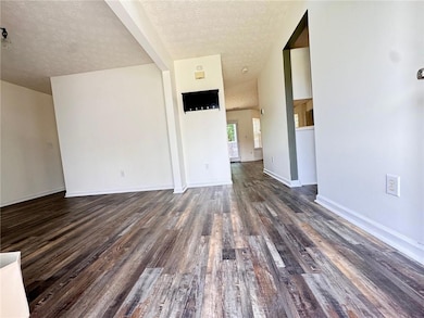 Unfurnished living room with baseboards, a texture