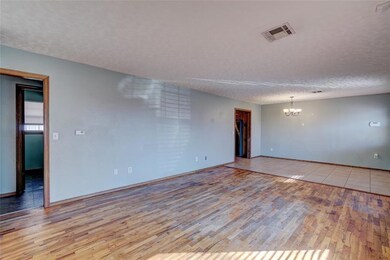 Tiled empty room featuring an inviting chandelier 