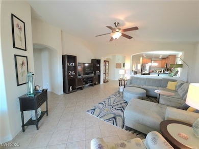 Living room with arched walkways, a ceiling fan, and light tile patterned floors