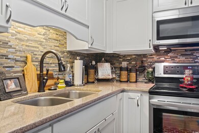 Kitchen with sink, white cabinetry, decorative bac
