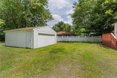 View of yard with an outdoor structure, a detached garage, and view of wooded area