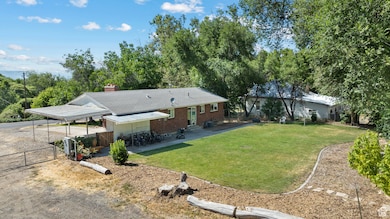 Rear view of house featuring entry steps, driveway, a gate, a detached carport, and a chimney