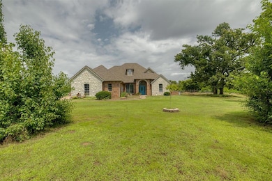 French country inspired facade featuring stone siding, a front yard, and brick siding