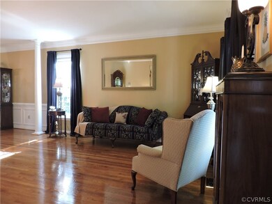 Formal living room has crown molding and wood floo