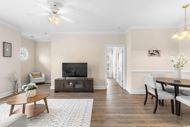 Living area featuring ornamental molding, light wood-style floors, a ceiling fan, and a chandelier