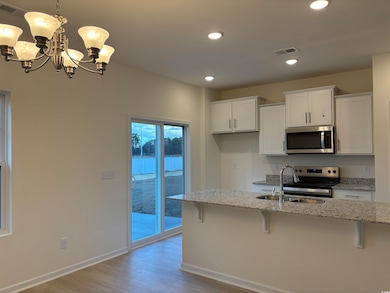 Kitchen with white cabinetry, light stone countert