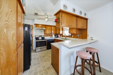 Kitchen with black appliances, a ceiling fan, a si