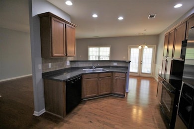 Kitchen with black appliances, dark countertops, dark wood-type flooring, pendant lighting, and recessed lighting