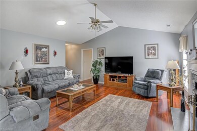 This large living room features vaulted ceiling, fireplace, and gleaming flooring.