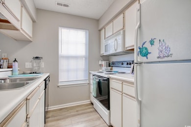 Kitchen with white cabinetry, light wood-type floo