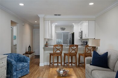 Living area featuring light wood-style floors, crown molding, and recessed lighting