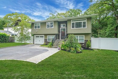 Split foyer home with stone siding, a garage, and asphalt driveway