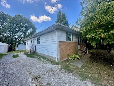 View of property exterior with an outdoor structure, entry steps, brick siding, and a detached garage
