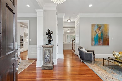 Entrance foyer featuring ornate columns, ornamental molding, wood finished floors, stairs, and a ceiling fan