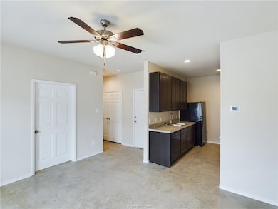 Kitchen with dark brown cabinetry, black fridge, c