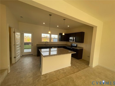 Kitchen with stainless steel appliances, light stone counters, hanging light fixtures, a center island, and recessed lighting