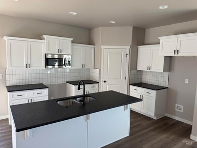 Kitchen featuring stainless steel microwave, backsplash, dark wood finished floors, recessed lighting, and white cabinets