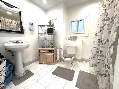 Full bathroom with curtained shower and light marble finish flooring