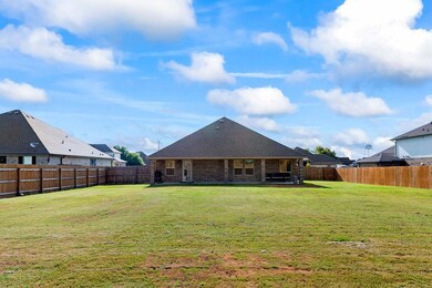 Rear view of house with a fenced backyard, brick siding, a patio, and a shingled roof