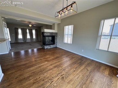 Unfurnished living room with dark wood-style floors, plenty of natural light, and a stone fireplace