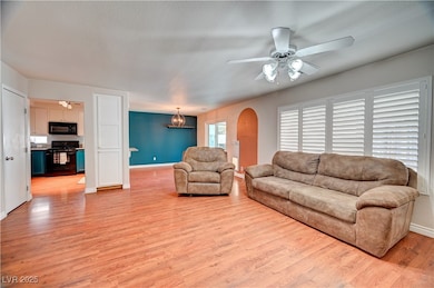 Living room with light wood finished floors, ceiling fan, a chandelier, and a textured ceiling