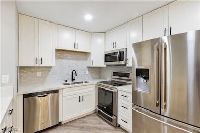 Kitchen with a sink, light countertops, appliances