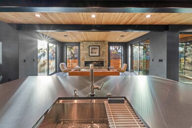 Kitchen view of a fireplace, a wood ceiling with exposed beams, dark countertops, and recessed lighting