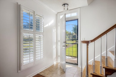 Entryway featuring stairs, a textured ceiling, ornamental molding, and light tile patterned floors