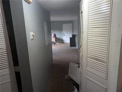 Corridor featuring a textured ceiling and electric panel