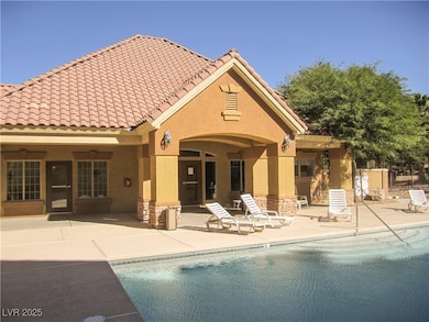 Back of property with stone siding, stucco siding, and a tiled roof