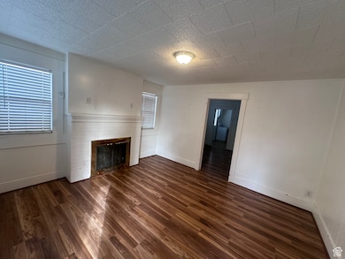 Unfurnished living room with dark hardwood / wood-style flooring and a fireplace