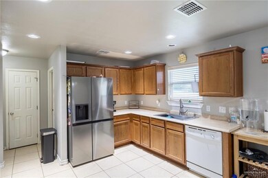 Kitchen with light tile flooring, sink, stainless steel fridge with ice dispenser, and dishwasher