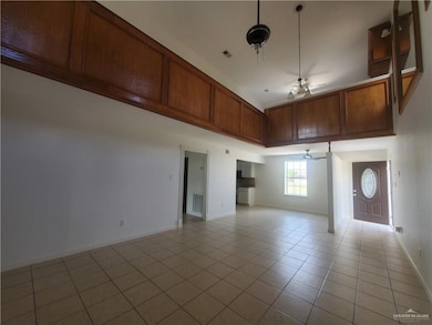 Unfurnished room featuring a towering ceiling, ceiling fan, and light tile patterned floors
