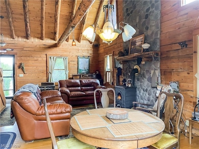 Dining room with wood walls, wooden ceiling, beamed ceiling, a wood stove, and light wood-type flooring