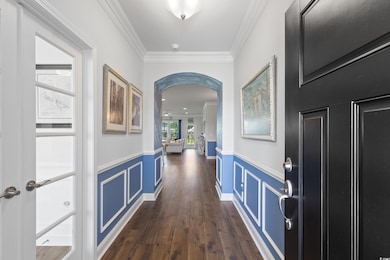 Hallway with crown molding, wainscoting, dark wood-style floors, and arched walkways