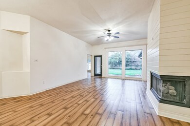 Looking through the large family room which features wood-look vinyl flooring, ceiling fan and a corner art niche