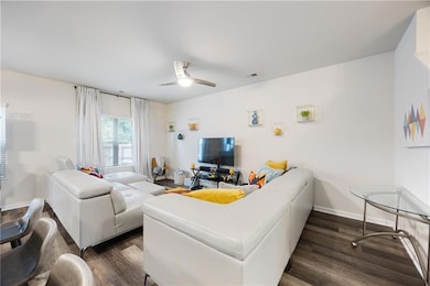 Living area featuring dark wood-style flooring and a ceiling fan
