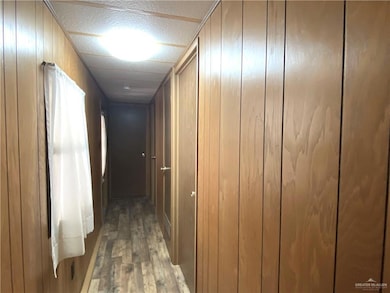 Hallway featuring wood walls and dark wood-type flooring
