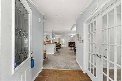 Foyer entrance with crown molding, carpet floors, 
