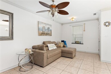 Living room featuring crown molding, light tile patterned floors, and ceiling fan