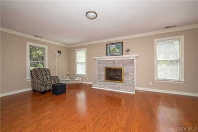 Great Room with brick fireplace with gas logs and wood floors.