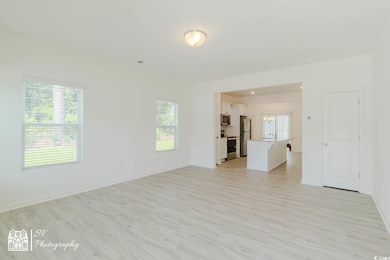 Unfurnished living room with light wood-style flooring, a chandelier, and baseboards