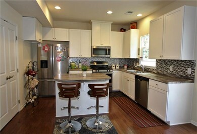 The kitchen features white cabinets, stainless app