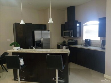 Kitchen featuring appliances with stainless steel finishes, dark cabinetry, a breakfast bar area, and hanging light fixtures