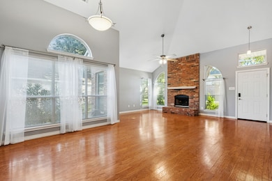 Dining and Living Room featuring high vaulted ceiling, hardwood floors, a fireplace, and ceiling fan.