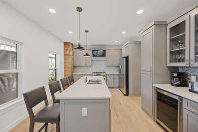 Kitchen featuring gray cabinets, a kitchen bar, glass insert cabinets, wine cooler, and recessed lighting