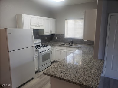 Kitchen with white appliances, a sink, under cabin