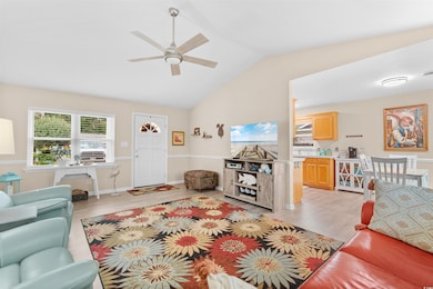 Living room featuring vaulted ceiling, light wood-type flooring, and ceiling fan
