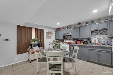 Kitchen with light stone countertops, tasteful backsplash, light tile flooring, gray cabinets, and sink